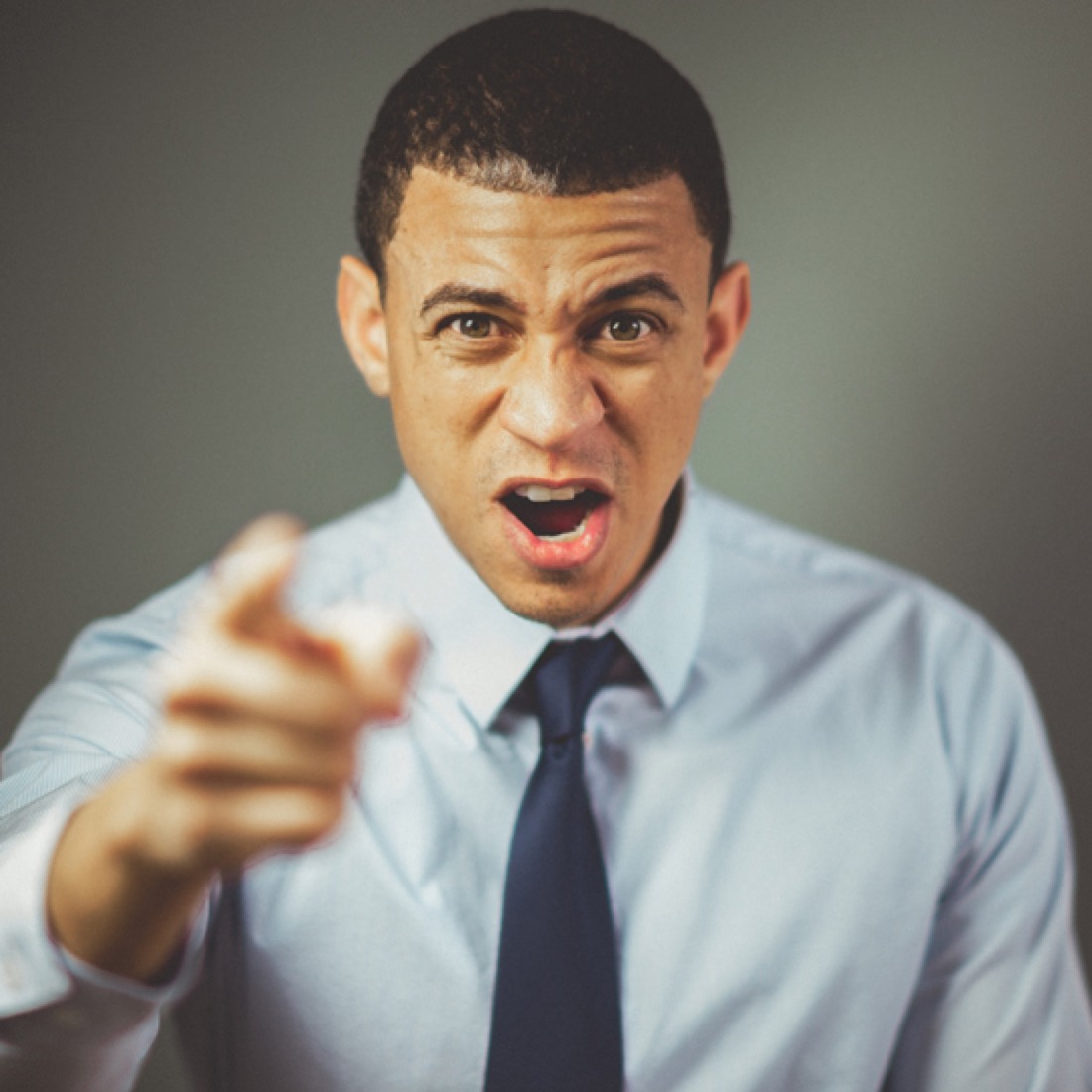 Presenter in a shirt and tie speaking with energy and pointing