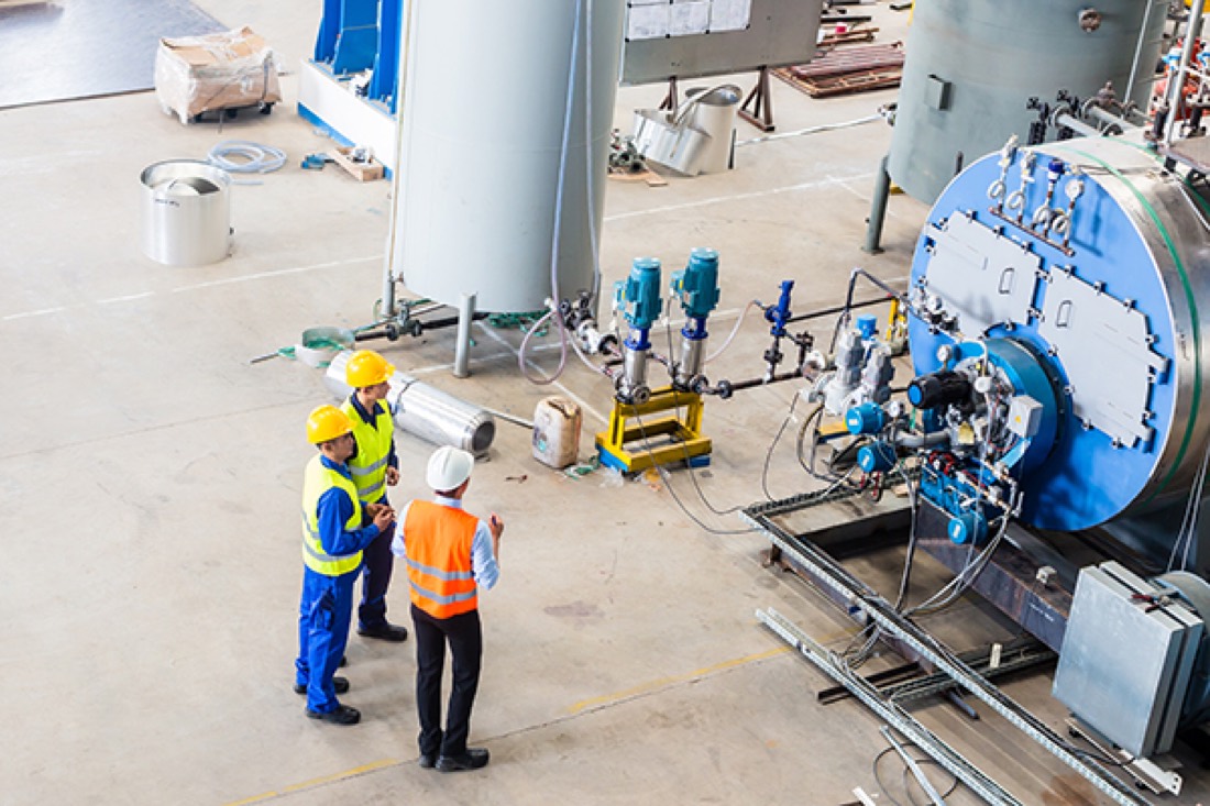 Workers in hard hats reviewing equipment in a process plant